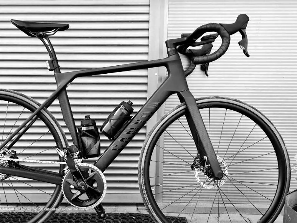 Close-up of a black road bike in front of a metal shutter.